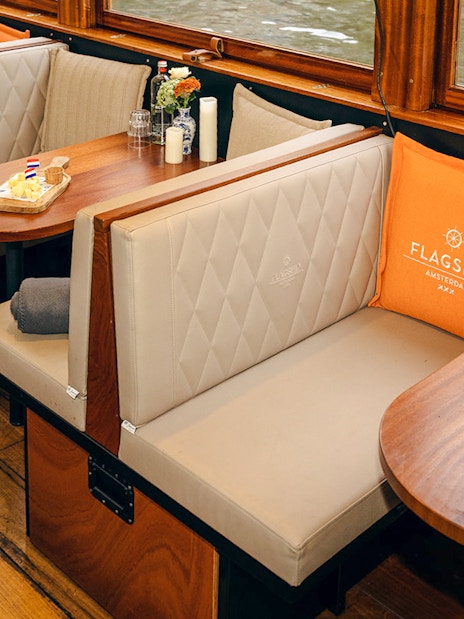 Cozy seating with snacks on a wooden table inside a canal boat in Amsterdam.