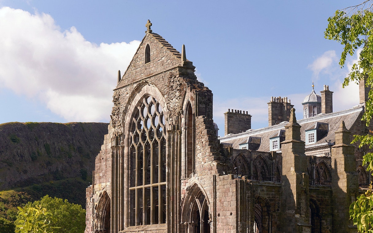 Palace of Holyroodhouse ruins with arched windows and stone facade in Edinburgh.