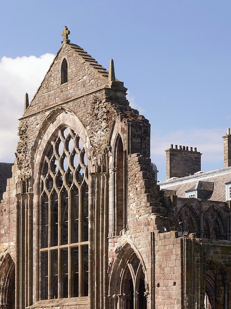Palace of Holyroodhouse ruins with arched windows and stone facade in Edinburgh.