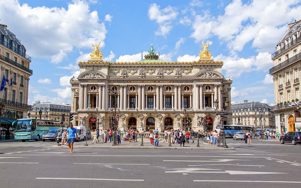 Opera Garnier facade with people and traffic in Paris, France.