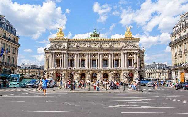 Opera Garnier facade with people and traffic in Paris, France.