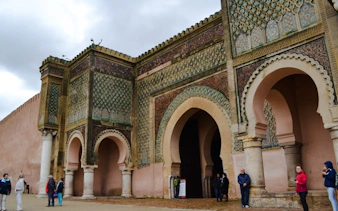 Bab Mansour gate in Meknes with visitors exploring the historic architecture.