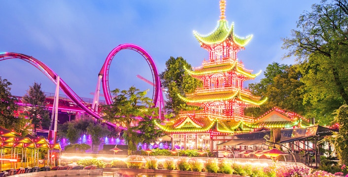 Tivoli Gardens illuminated pagoda and roller coaster at dusk.