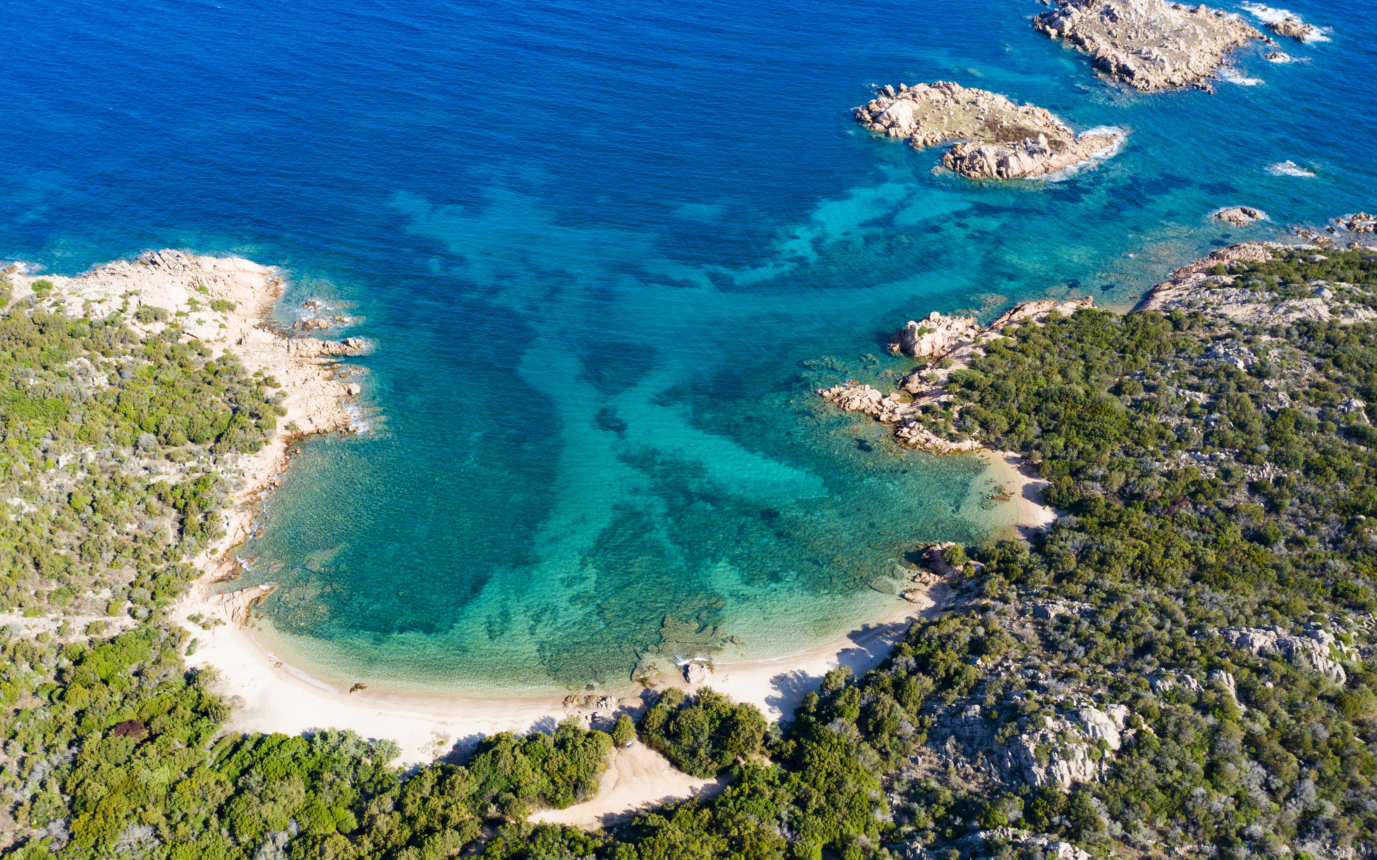 Aerial view of a secluded beach and turquoise waters on the Emerald Coast, Italy.