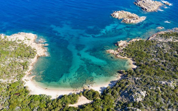 Aerial view of a secluded beach and turquoise waters on the Emerald Coast, Italy.