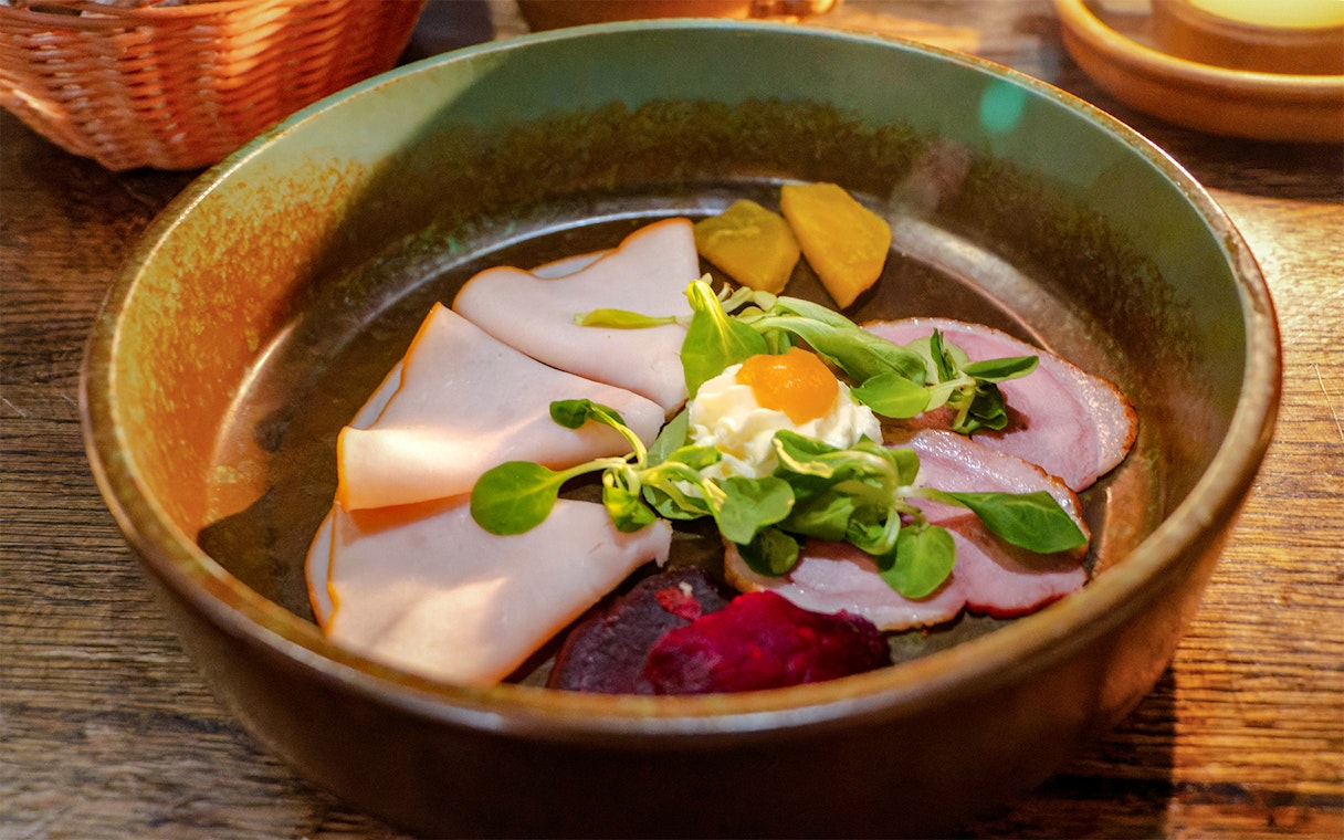 Medieval dinner show appetizer plate with meats, greens, and pickled vegetables.