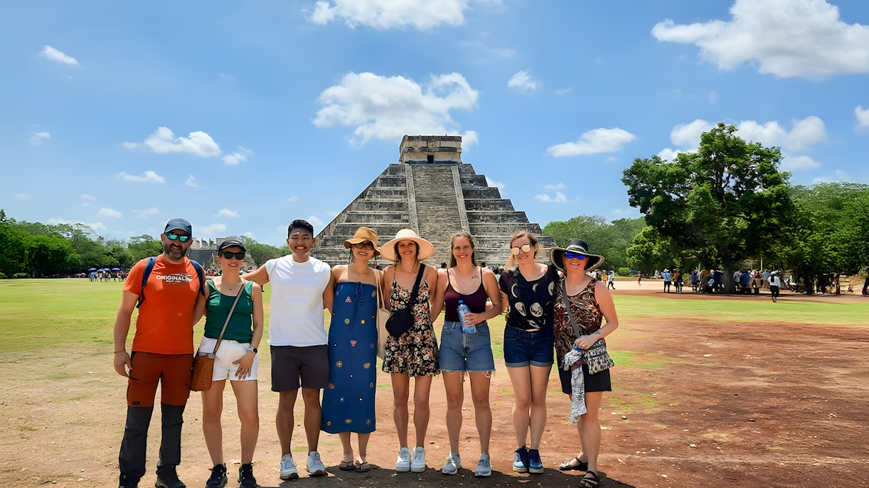 Tourists with guide in front of Chichen Itza pyramid in Mexico.