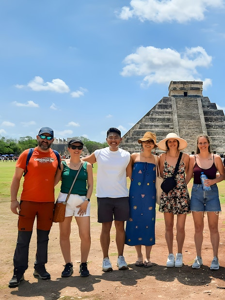 Tourists with guide in front of Chichen Itza pyramid in Mexico.