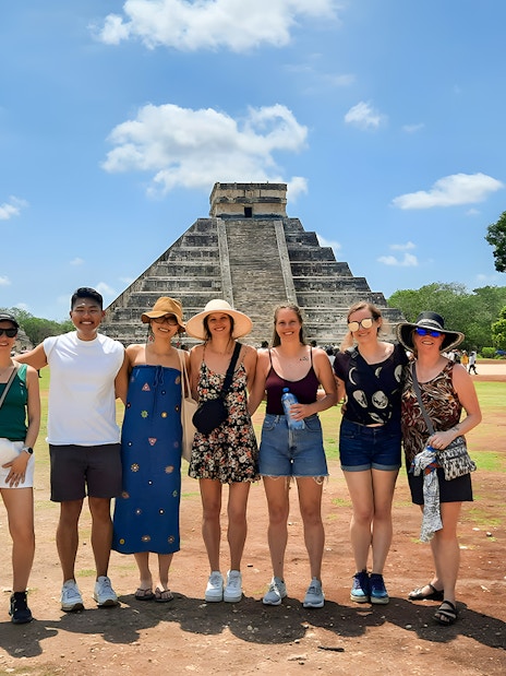 Tourists with guide in front of Chichen Itza pyramid in Mexico.
