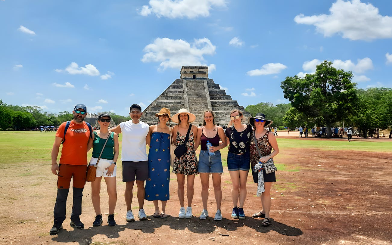Tourists with guide in front of Chichen Itza pyramid in Mexico.