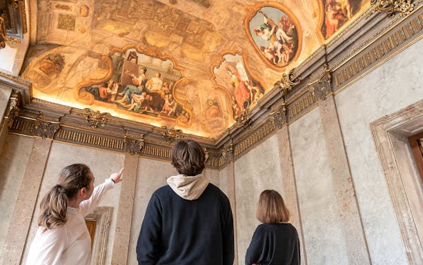 Visitors admire ornate ceiling frescoes during Palais Lobkowitz audio guide tour.
