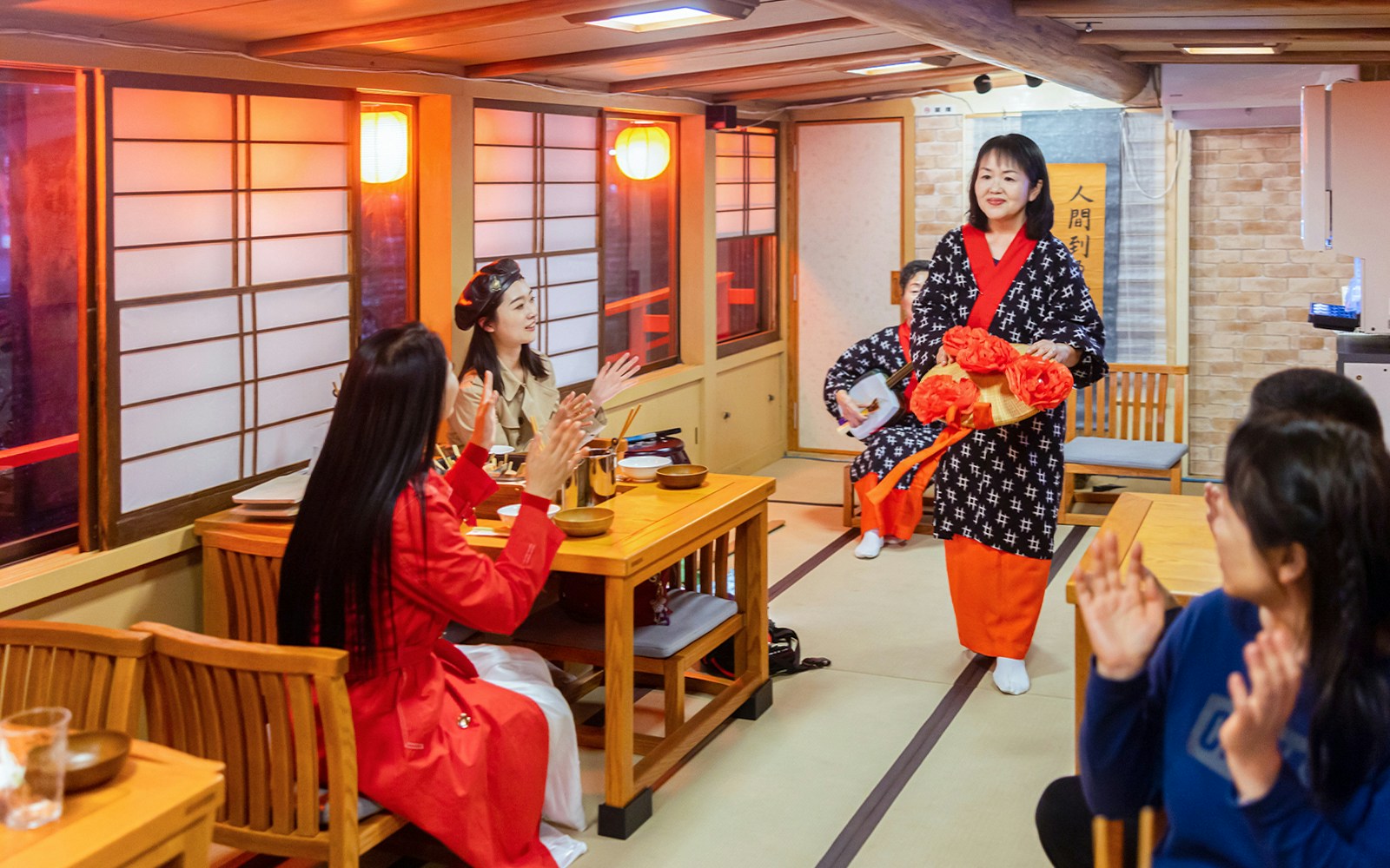 Guests enjoying a shamisen performance on a traditional Yakatabune hot pot dinner cruise in Japan.