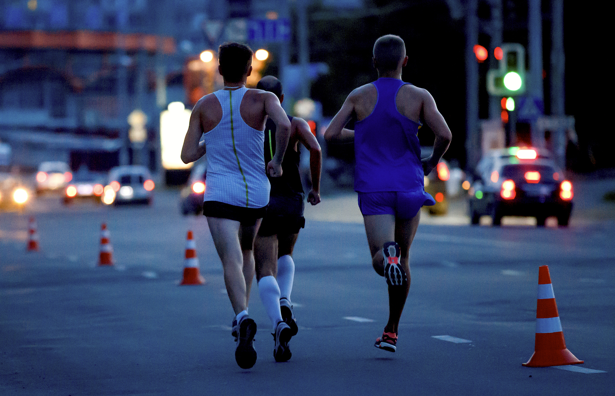 Group running a midnight marathon through illuminated city streets.