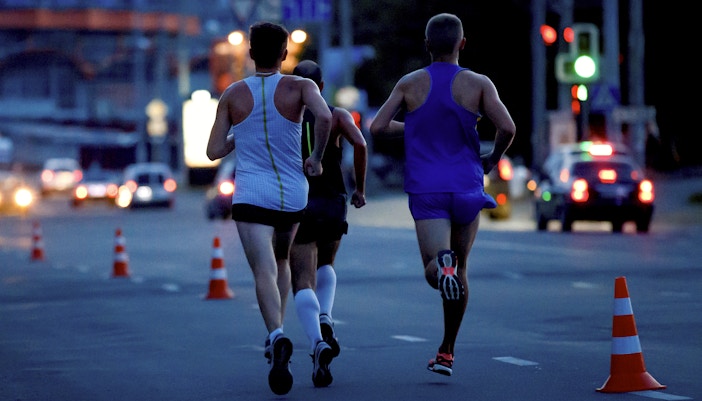 Group running a midnight marathon through illuminated city streets.