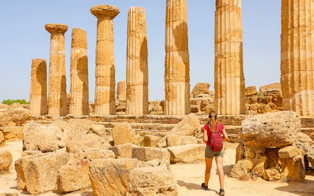 Young woman exploring ancient ruins at Valley of the Temples, Agrigento, Sicily.