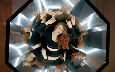 Person surrounded by mirrors creating multiple reflections at the World of Illusions exhibit.