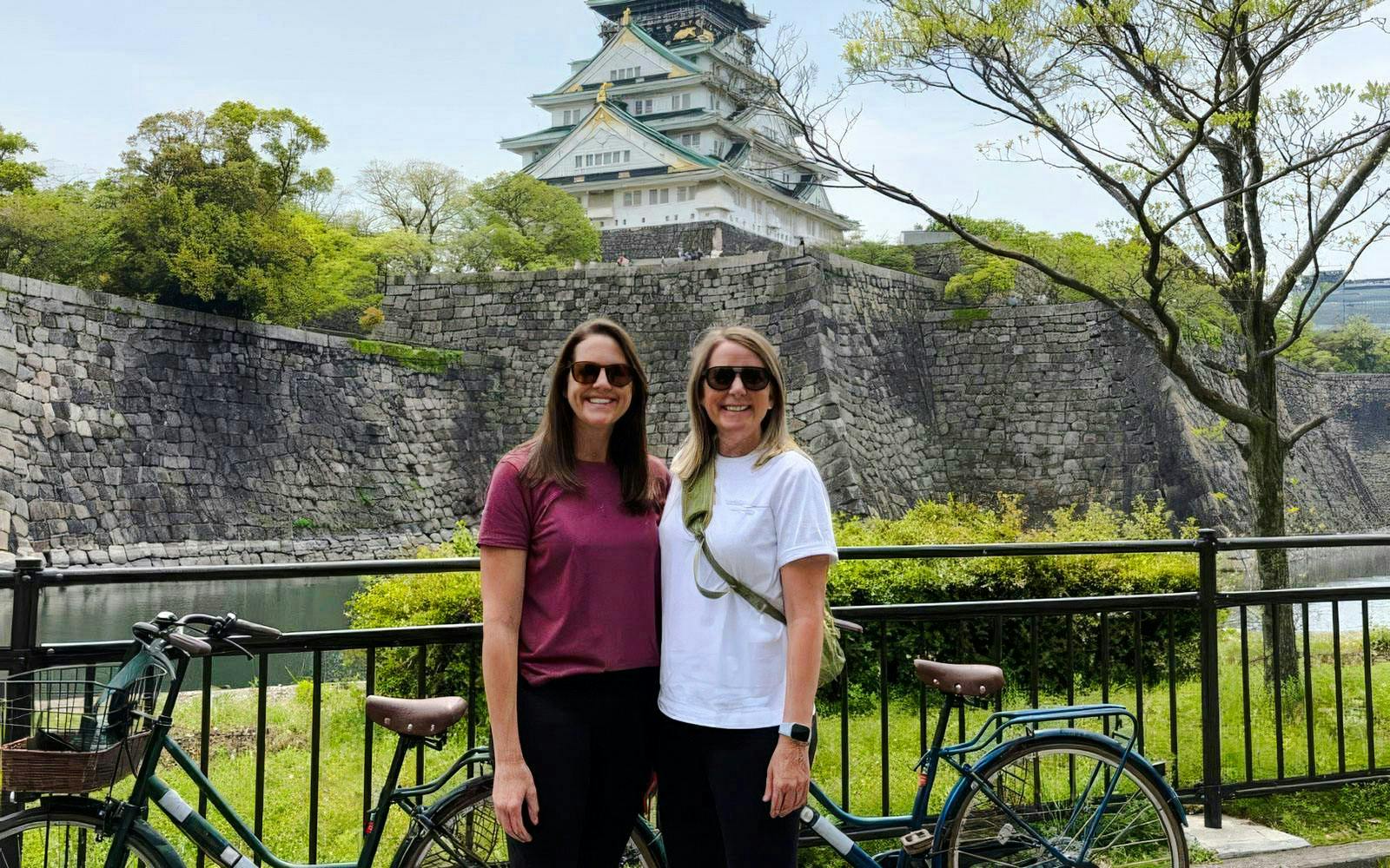 Two women with bicycles in front of Osaka Castle, Japan.