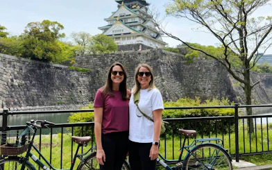 Two women with bicycles in front of Osaka Castle, Japan.