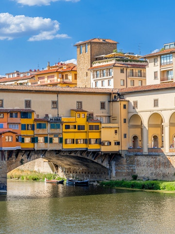 Vasari Corridor above Ponte Vecchio in Florence, Italy, with colorful buildings and river below.