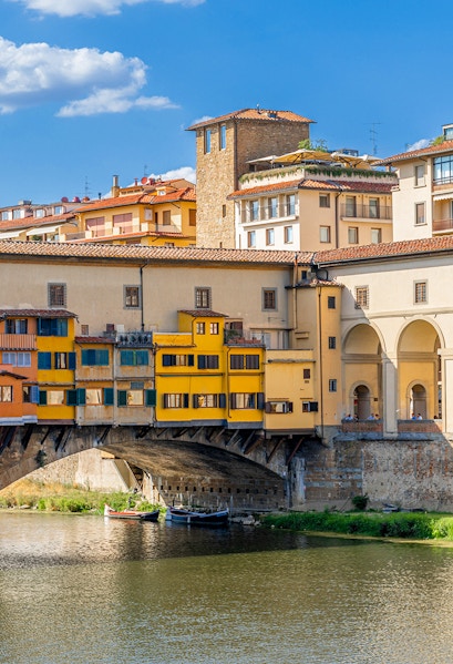 Vasari Corridor above Ponte Vecchio in Florence, Italy, with colorful buildings and river below.