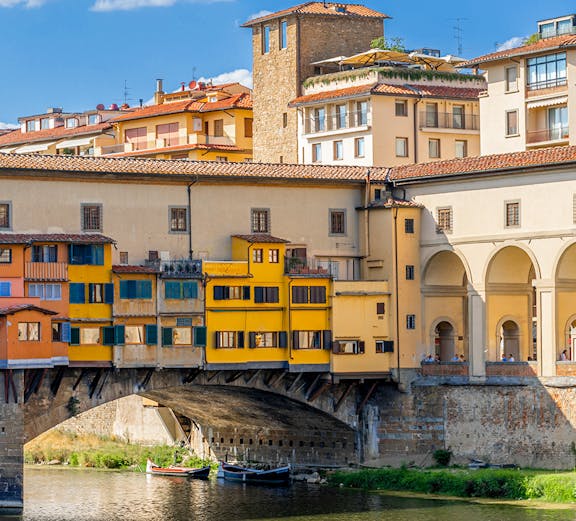 Vasari Corridor above Ponte Vecchio in Florence, Italy, with colorful buildings and river below.