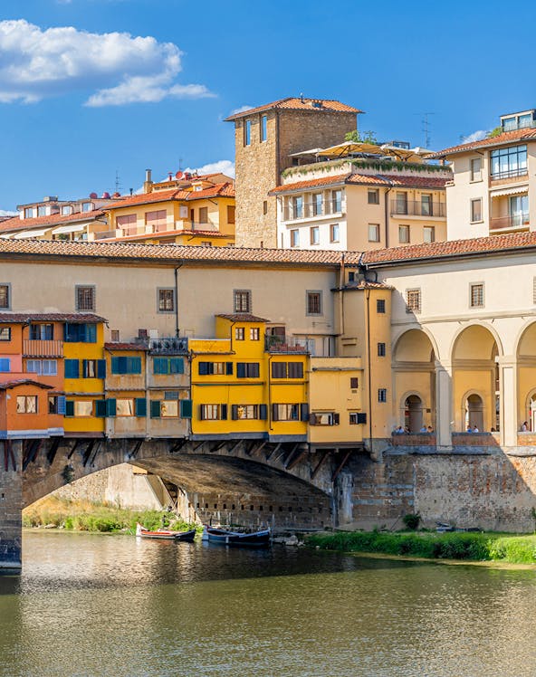Vasari Corridor above Ponte Vecchio in Florence, Italy, with colorful buildings and river below.
