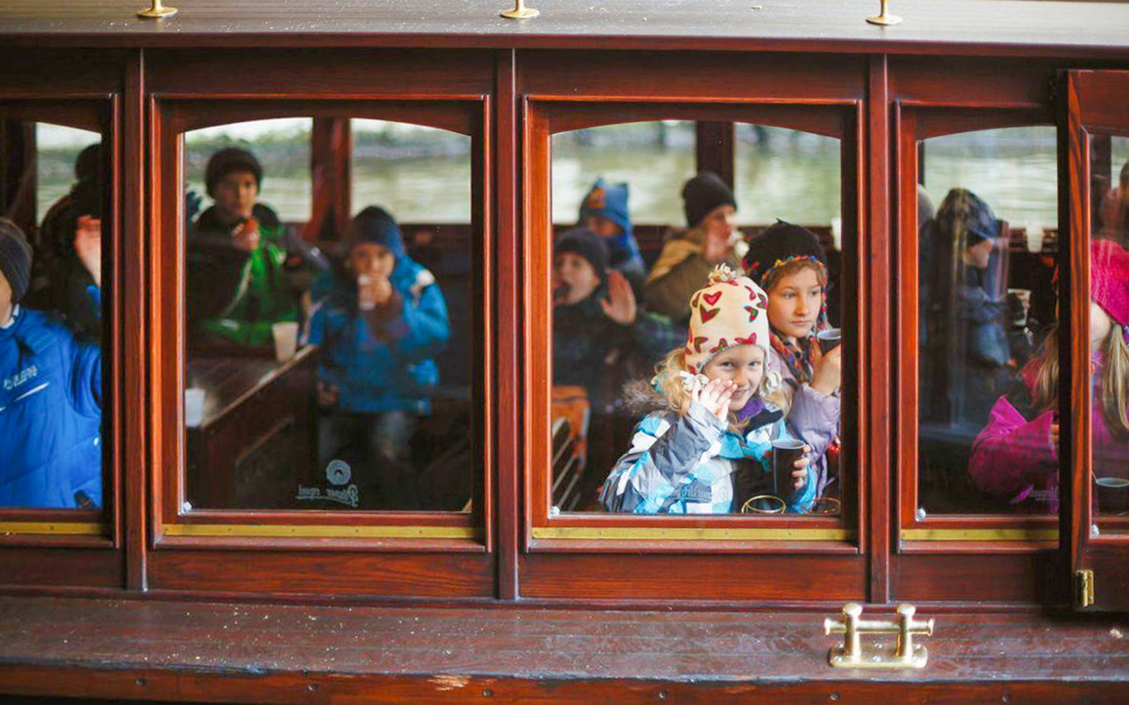 Children enjoying a Prague sightseeing cruise with drinks and snacks.