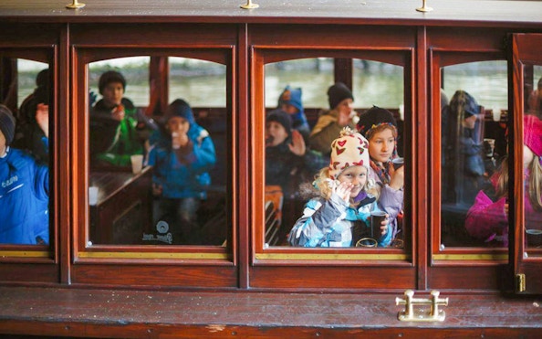 Children enjoying a Prague sightseeing cruise with drinks and snacks.