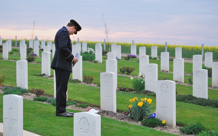 Person in uniform at Somme Battlefields cemetery, France, with rows of white gravestones.