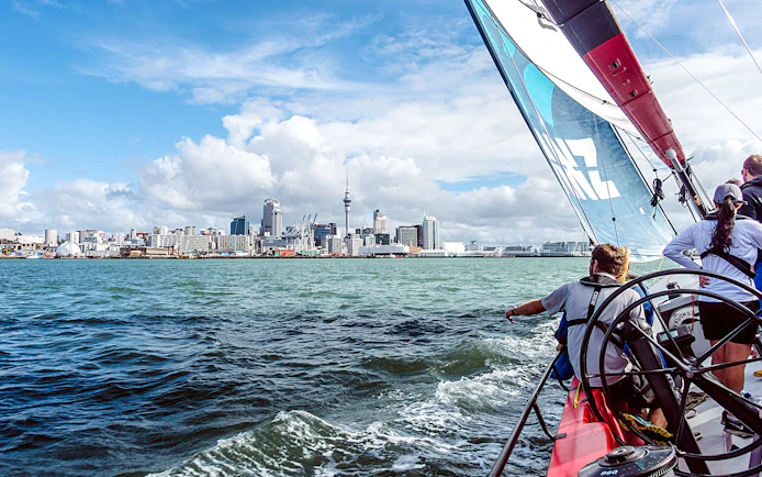 Sailing on Waitemata Harbour with Auckland skyline in view during America's Cup experience.