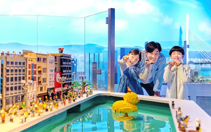 Family enjoying LEGO cityscape and duck model at LEGOLAND Discovery Center Osaka.