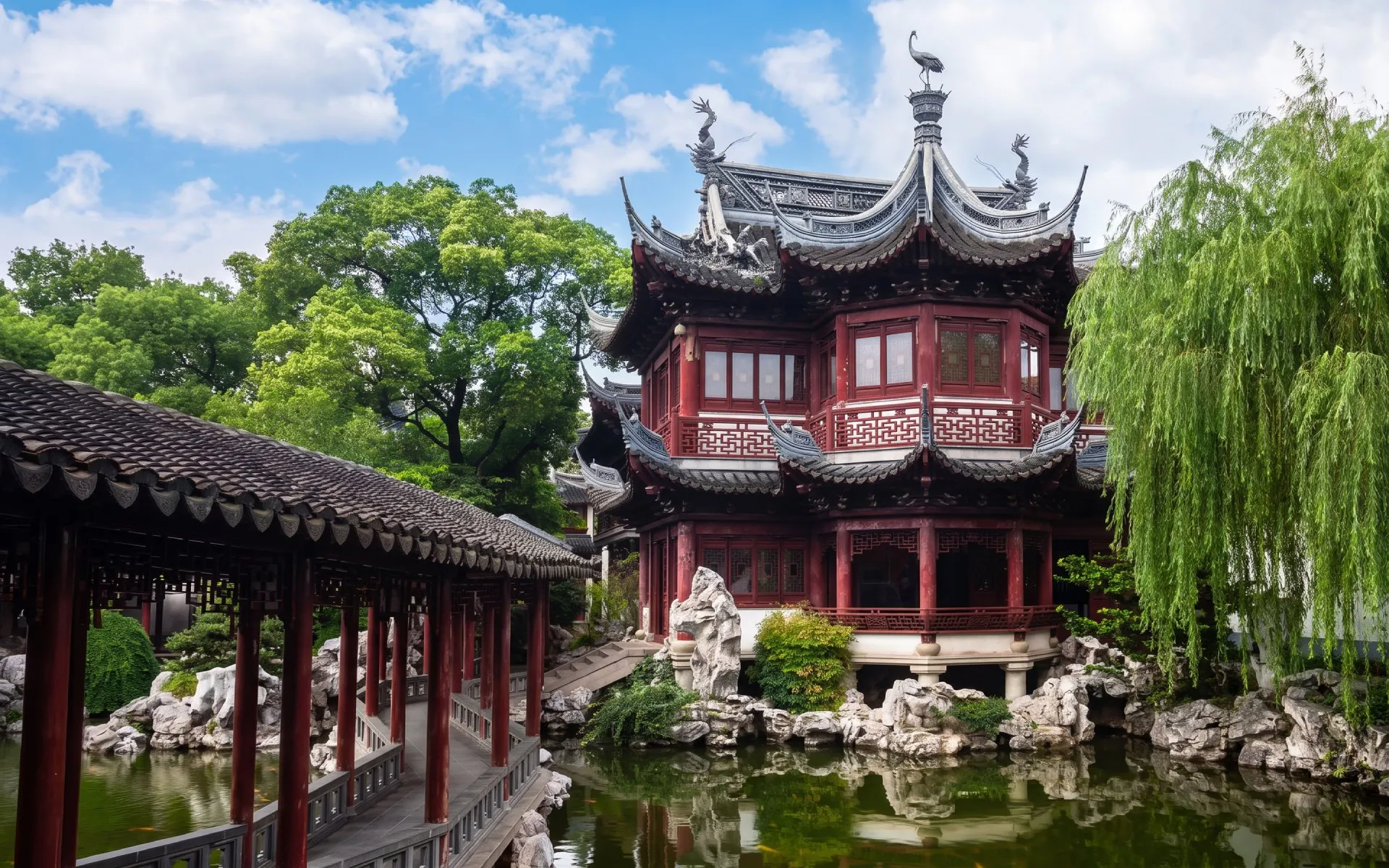 Traditional pavilion and bridge in Yu Garden, Shanghai, China, surrounded by lush greenery.