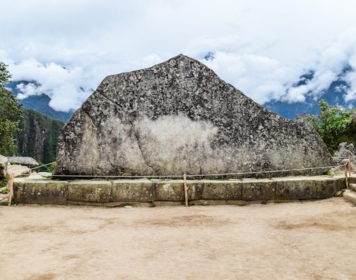 Sacred stone at Machu Picchu with mountain backdrop.