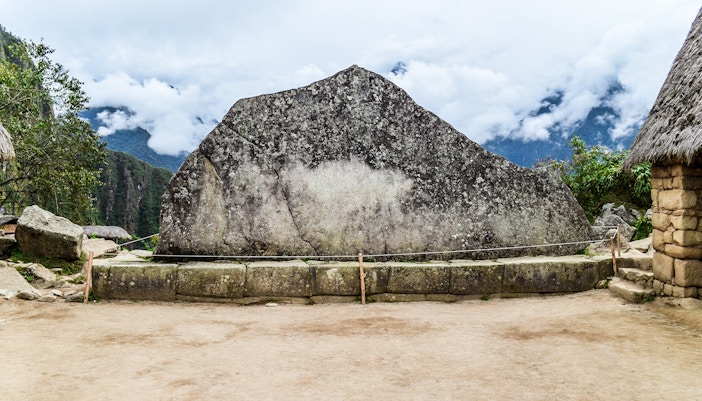 Sacred stone at Machu Picchu with mountain backdrop.