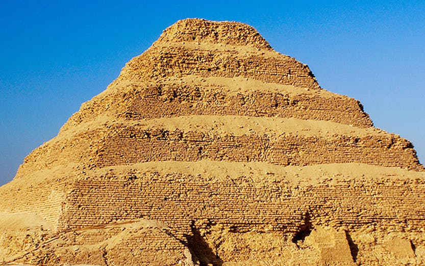 Step Pyramid of Djoser in Saqqara, Egypt under a clear blue sky.