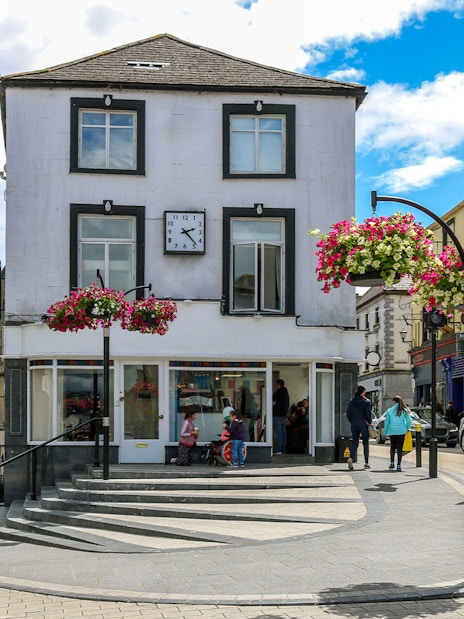 Central street in Kilkenny's old town with shops and hanging flowers.