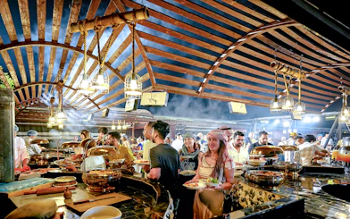 Guests enjoying buffet dinner under wooden canopy during evening desert safari.