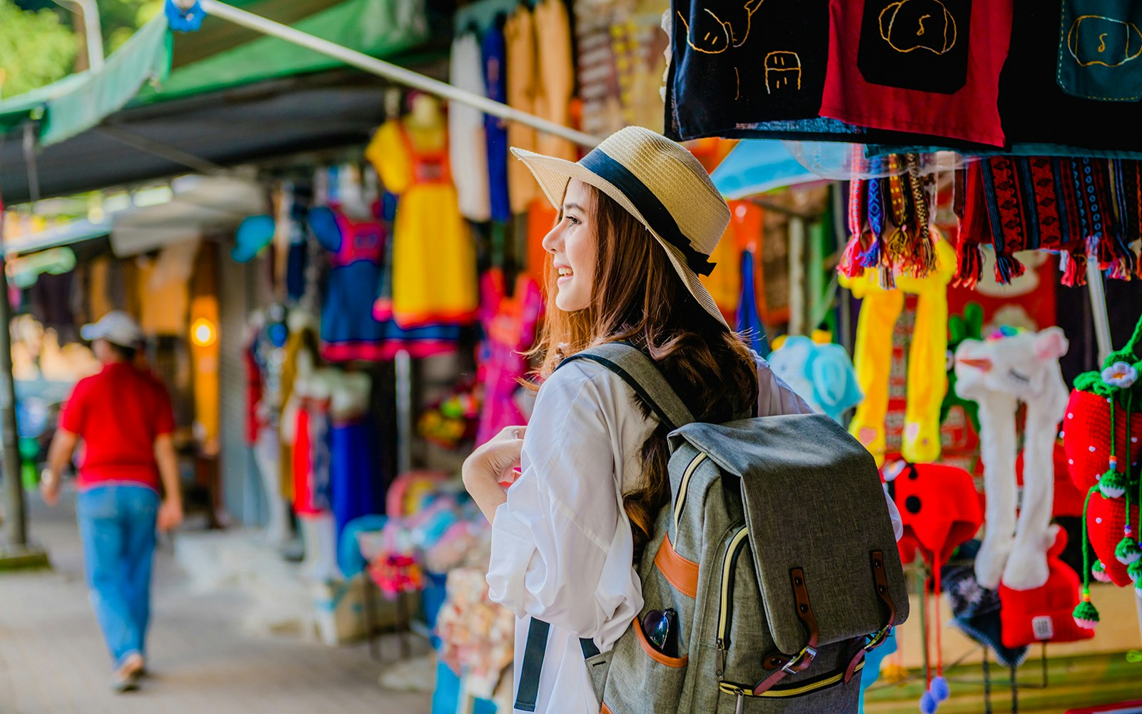Traveler with a backpack exploring a colorful market in Doi Pui village, Thailand.