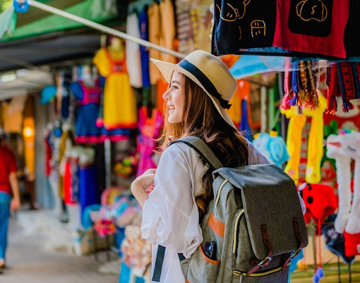 Traveler with a backpack exploring a colorful market in Doi Pui village, Thailand.