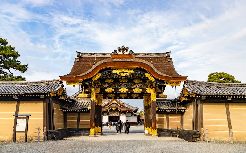 Entrance gate of Nijo Castle in Kyoto, Japan, with ornate wooden carvings and gold accents.