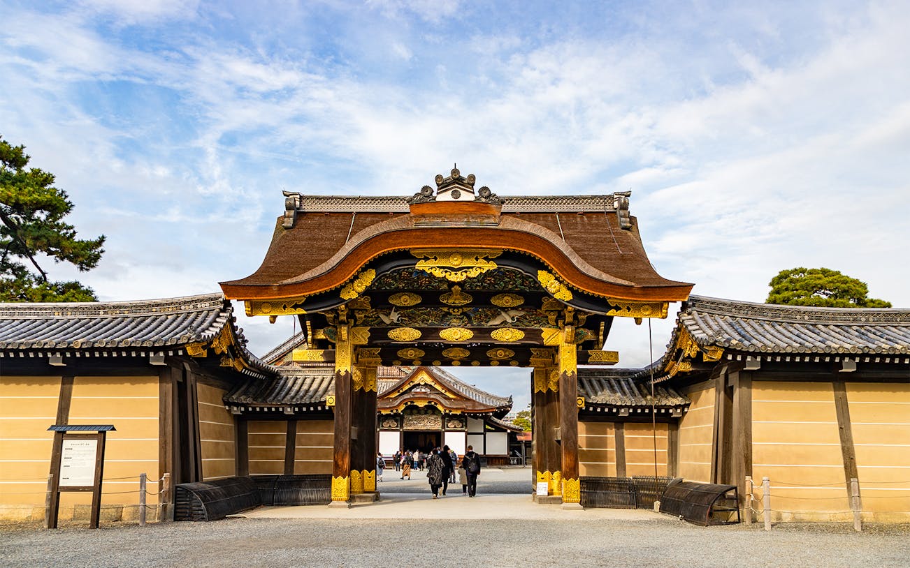 Entrance gate of Nijo Castle in Kyoto, Japan, with ornate wooden carvings and gold accents.