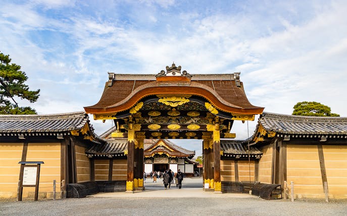 Entrance gate of Nijo Castle in Kyoto, Japan, with ornate wooden carvings and gold accents.