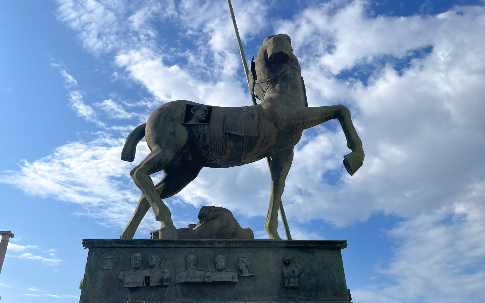 Bronze centaur statue at Pompeii archaeological site under blue sky.