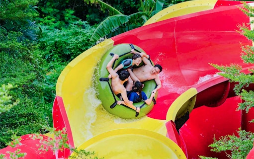 Visitors enjoying a raft ride on a colorful water slide at Ancol Atlantis Water Adventure Park.