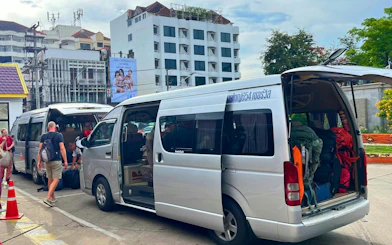 Minivans loading luggage for private transfer from Chiang Mai Airport to city hotel.