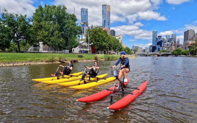 People riding waterbikes on the Yarra River with Melbourne skyline in the background.