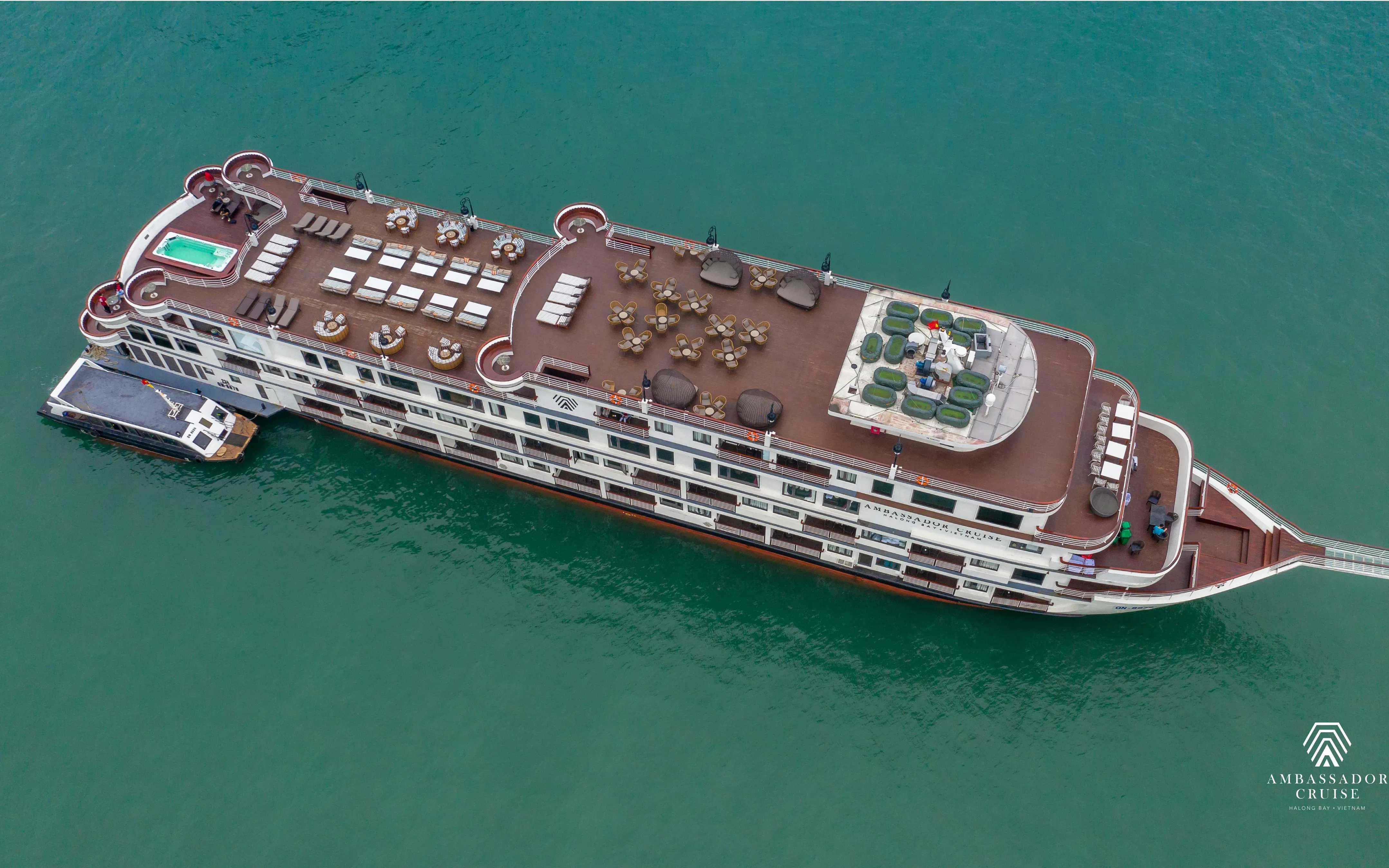 Aerial view of 5-star Ambassador Cruise ship in Ha Long Bay, featuring spacious deck and seating areas.