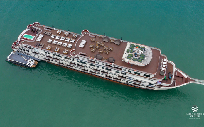 Aerial view of 5-star Ambassador Cruise ship in Ha Long Bay, featuring spacious deck and seating areas.