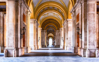 Royal Palace of Caserta interior with grand arched hallway and ornate columns.