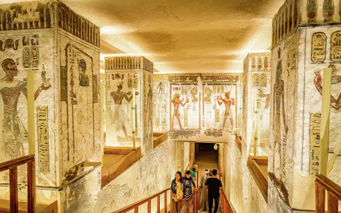 Ancient Egyptian tomb with hieroglyphs and tourists exploring in Luxor.